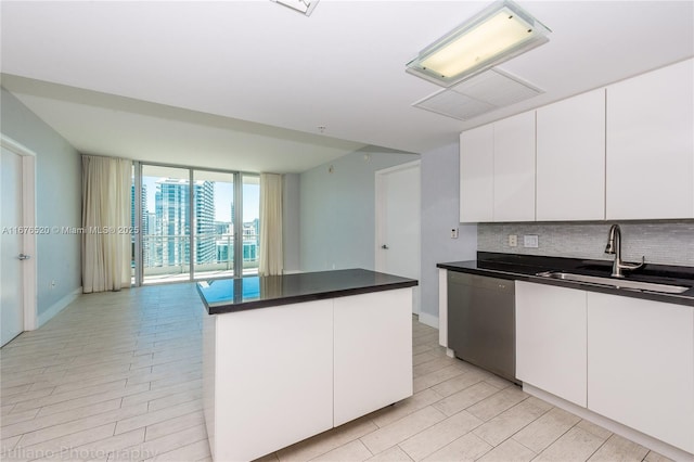 kitchen featuring white cabinets, sink, a wall of windows, dishwasher, and a kitchen island