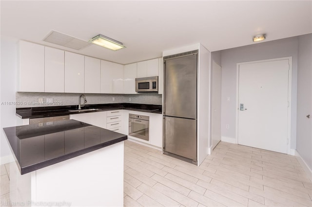 kitchen featuring white cabinets, appliances with stainless steel finishes, kitchen peninsula, and sink