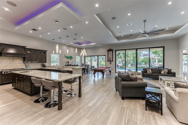 playroom featuring pool table, plenty of natural light, a tray ceiling, and light hardwood / wood-style flooring