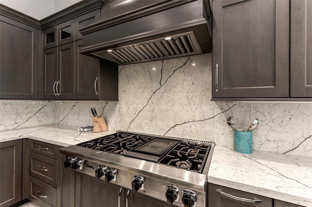 kitchen featuring dark brown cabinets, light stone countertops, stainless steel gas stovetop, and custom exhaust hood