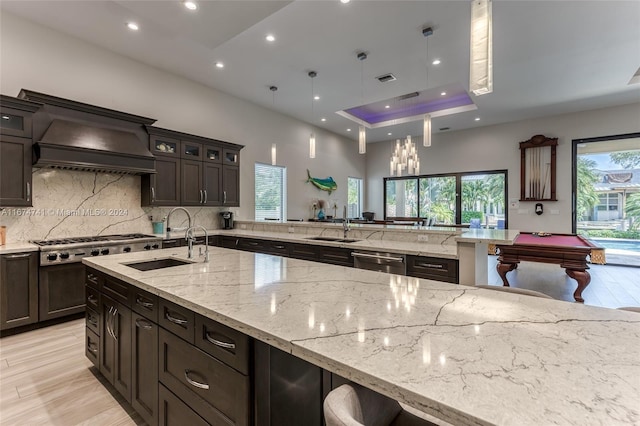 kitchen featuring custom exhaust hood, a tray ceiling, billiards, and light wood-type flooring