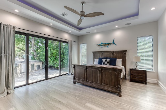 bedroom with ceiling fan, access to outside, a raised ceiling, and multiple windows