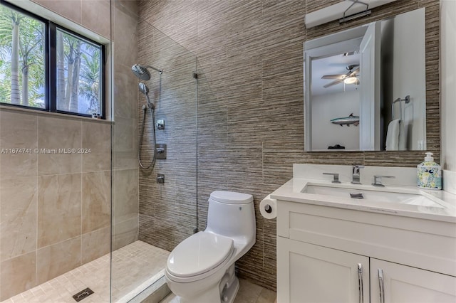 bathroom with a tile shower, ceiling fan, vanity, tile walls, and toilet