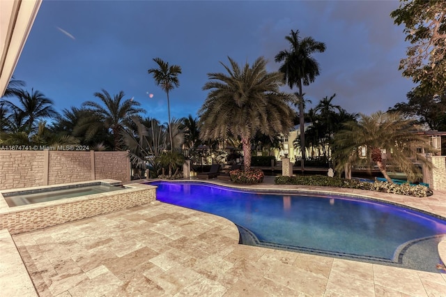 pool at dusk featuring an in ground hot tub and a patio area