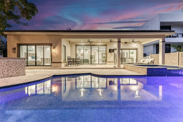 pool at dusk featuring ceiling fan and a patio area