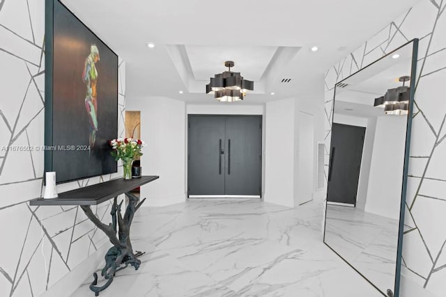 entrance foyer with an inviting chandelier and a raised ceiling