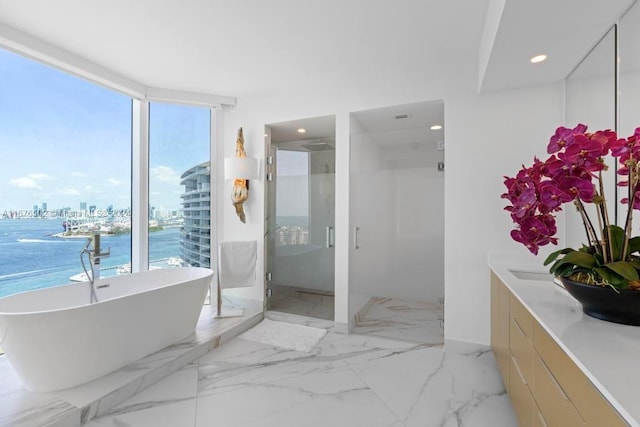 bathroom featuring vanity, separate shower and tub, and a water view