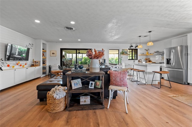 living room with a textured ceiling and light wood-type flooring