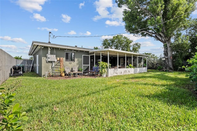 rear view of house featuring a yard and a sunroom