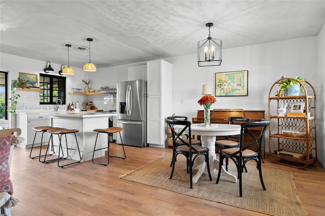 dining space with an inviting chandelier, light hardwood / wood-style flooring, and sink