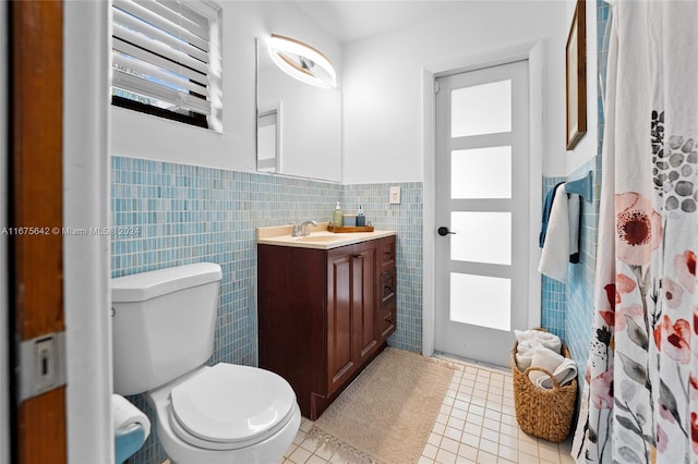 bathroom featuring toilet, vanity, tile walls, and tile patterned flooring