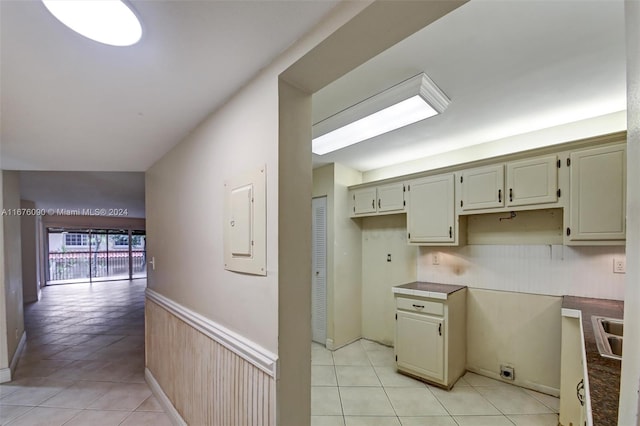 kitchen with cream cabinets, electric panel, and light tile patterned floors