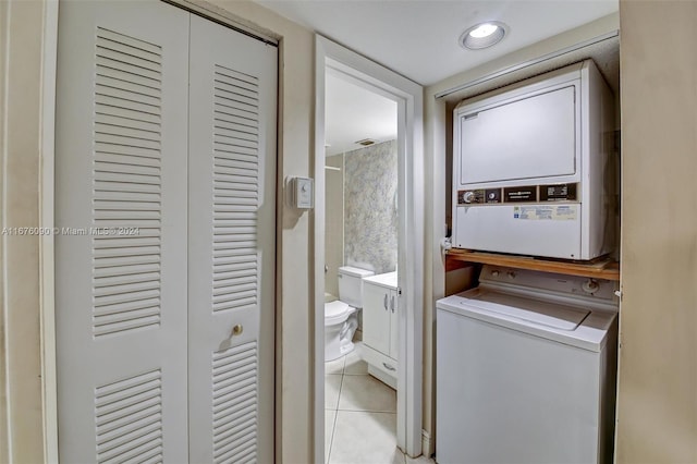 clothes washing area featuring stacked washer and dryer and light tile patterned floors