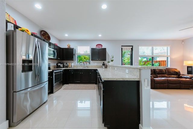 kitchen featuring stainless steel appliances, kitchen peninsula, light tile patterned flooring, and sink