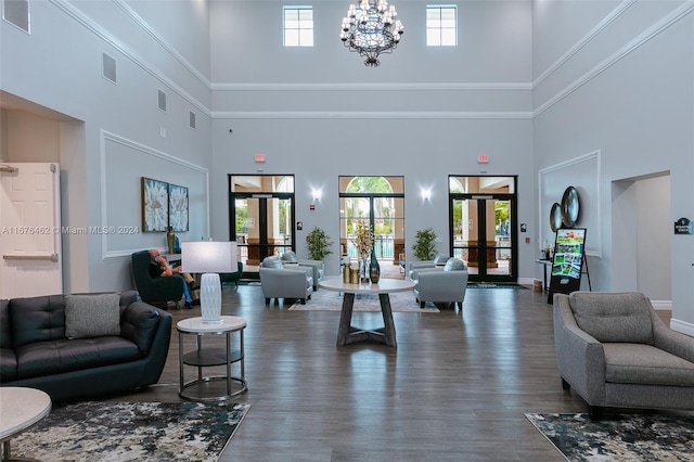 living room with a towering ceiling, french doors, dark hardwood / wood-style floors, and an inviting chandelier