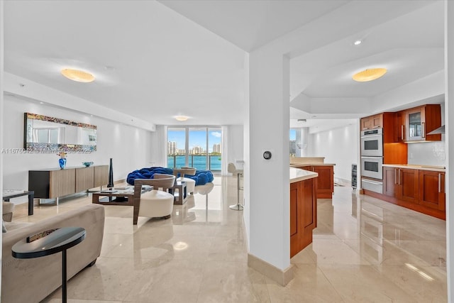 kitchen featuring stovetop, expansive windows, a water view, and double oven