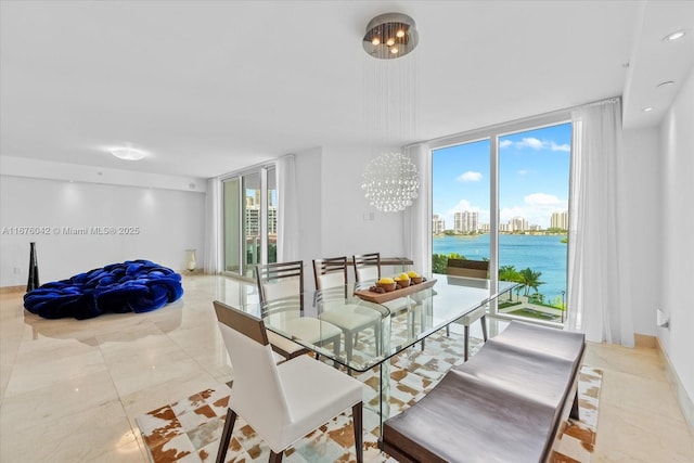 dining area with a chandelier, a water view, plenty of natural light, and a wall of windows