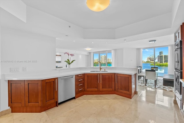 kitchen featuring sink, a water view, stainless steel dishwasher, and multiple ovens