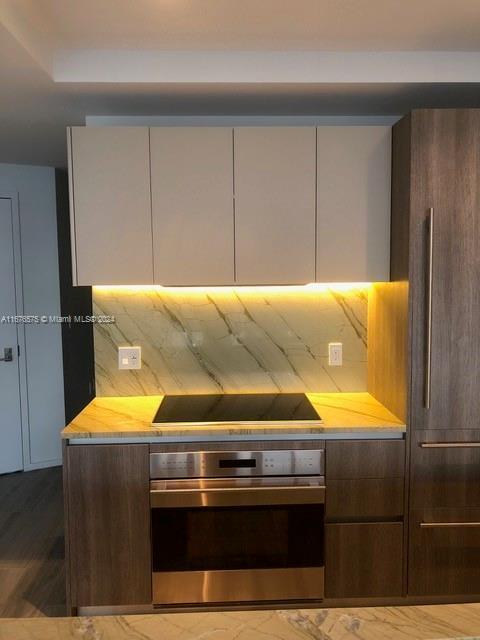 801 S Miami Ave Unit 3903, Miami, FL 33130 - kitchen with stainless steel oven, light countertops, black electric cooktop, modern cabinets, and wood finished floors