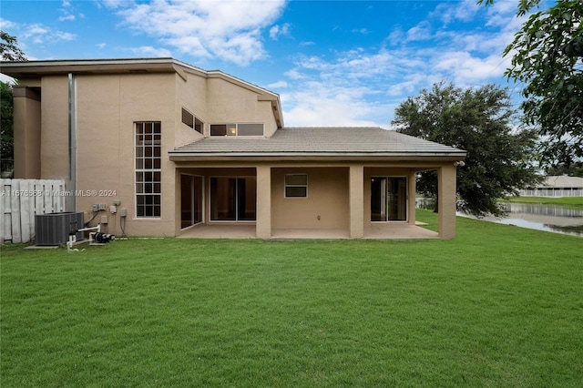 back of house with a yard, a patio, and a water view