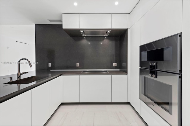 kitchen with white cabinets, black electric stovetop, sink, double oven, and tasteful backsplash