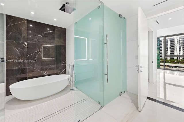 bathroom featuring plus walk in shower and tile walls