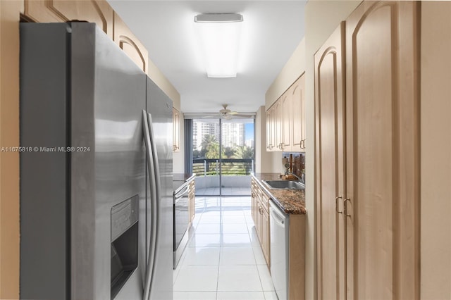 kitchen with ceiling fan, light tile patterned flooring, sink, appliances with stainless steel finishes, and dark stone counters