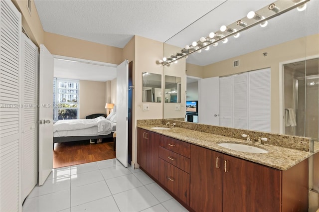 bathroom featuring tile patterned floors, a shower with shower door, vanity, and a textured ceiling