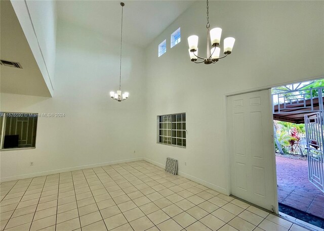 interior space featuring light tile patterned flooring, high vaulted ceiling, and an inviting chandelier