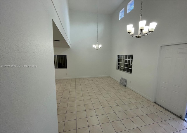 interior space with light tile patterned floors, a towering ceiling, and an inviting chandelier