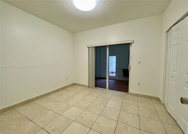 unfurnished bedroom with light tile patterned floors, a textured ceiling, and a closet