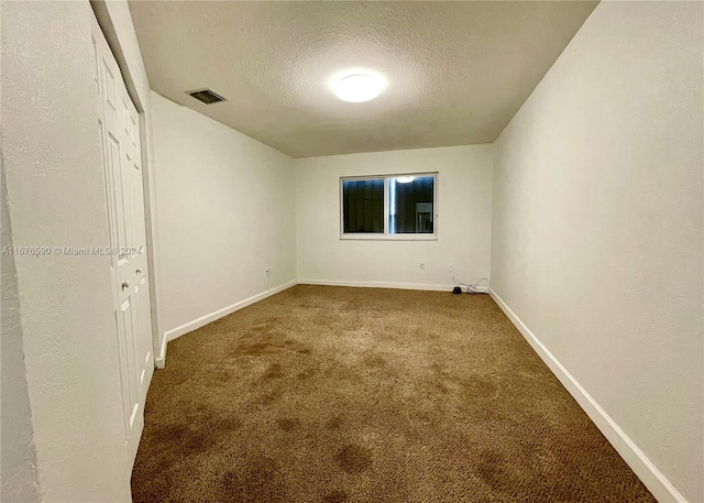 spare room featuring a textured ceiling and carpet floors