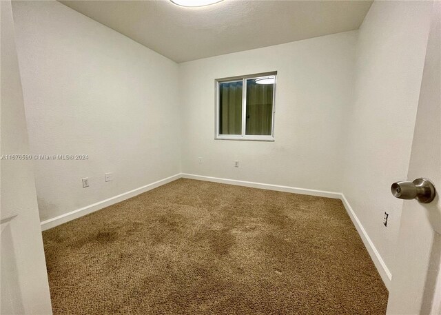 carpeted empty room featuring a textured ceiling