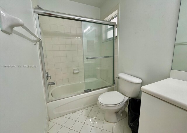 bathroom featuring tile patterned flooring, toilet, and enclosed tub / shower combo