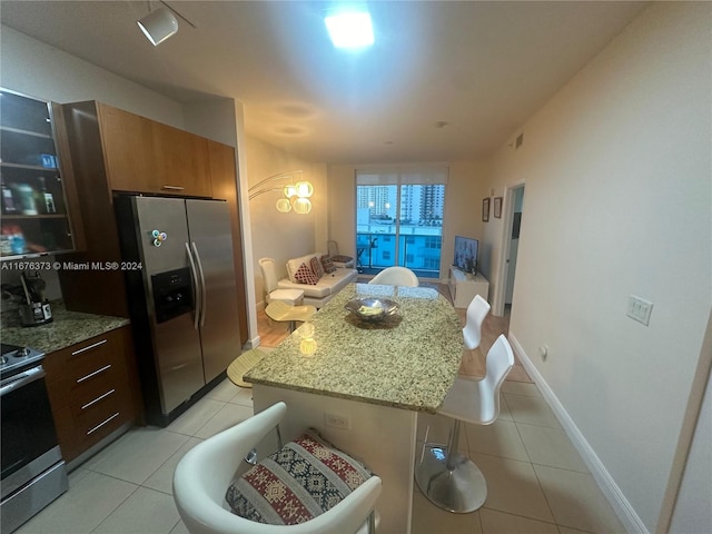 kitchen with light stone countertops, a center island, a kitchen breakfast bar, stainless steel appliances, and light tile patterned floors