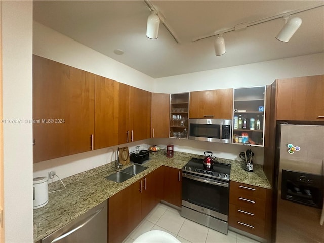 kitchen with stainless steel appliances, sink, light tile patterned flooring, rail lighting, and light stone counters