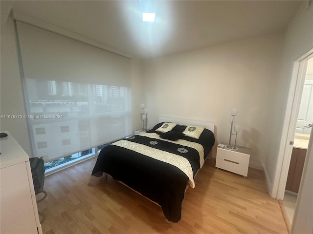 bedroom with ensuite bathroom and light wood-type flooring