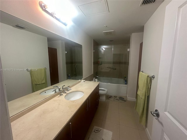 full bathroom with vanity, bath / shower combo with glass door, toilet, and tile patterned floors