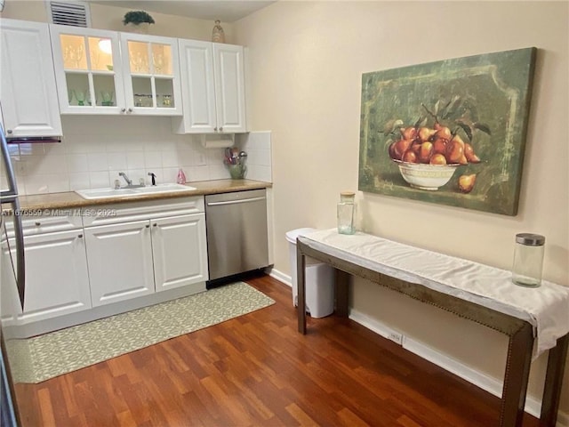 kitchen with dark wood finished floors, stainless steel dishwasher, glass insert cabinets, white cabinets, and a sink