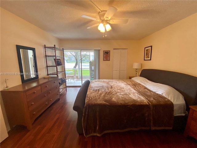 bedroom with dark wood-style floors, ceiling fan, access to exterior, a textured ceiling, and a closet