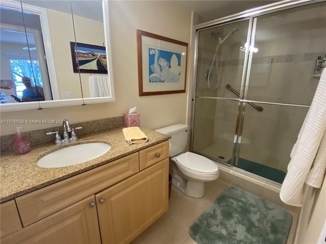 bathroom with toilet, vanity, a shower stall, and tile patterned floors