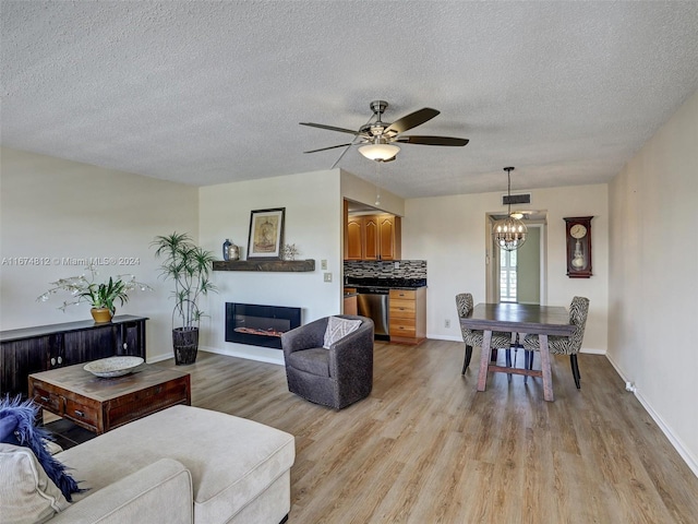 living room featuring light wood-type flooring, a textured ceiling, and ceiling fan with notable chandelier