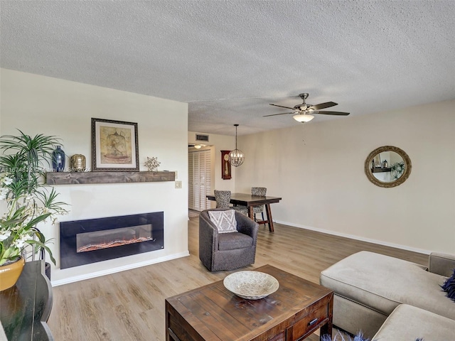 living room with light hardwood / wood-style flooring, a textured ceiling, and ceiling fan