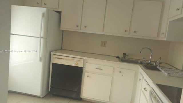 kitchen featuring white refrigerator, black dishwasher, sink, light tile patterned floors, and white cabinetry