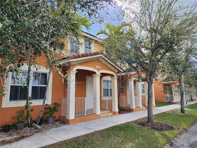 view of front of house featuring a porch, a tile roof, and stucco siding