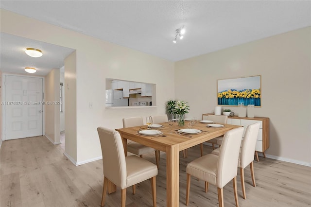 dining space featuring light hardwood / wood-style floors and a textured ceiling