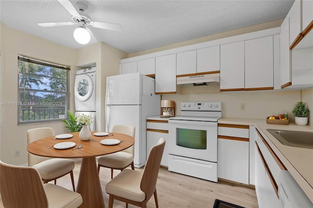 kitchen featuring white cabinets, a textured ceiling, light hardwood / wood-style flooring, stacked washer / dryer, and white appliances