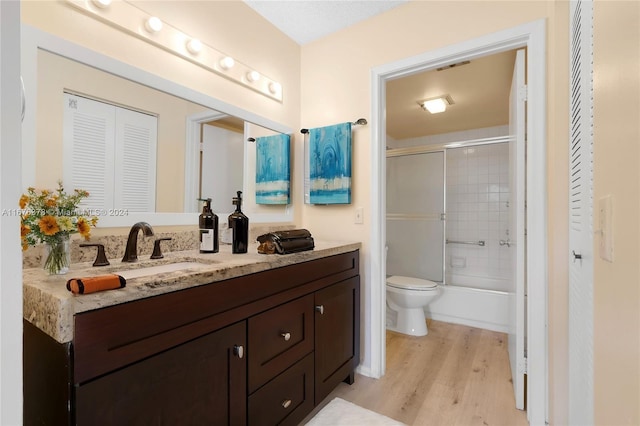 full bathroom featuring toilet, hardwood / wood-style floors, vanity, and shower / bath combination with glass door