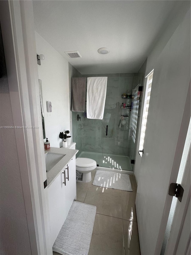 bathroom with toilet, an enclosed shower, vanity, and tile patterned flooring