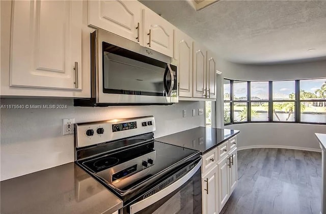 kitchen featuring appliances with stainless steel finishes, hardwood / wood-style floors, and white cabinets